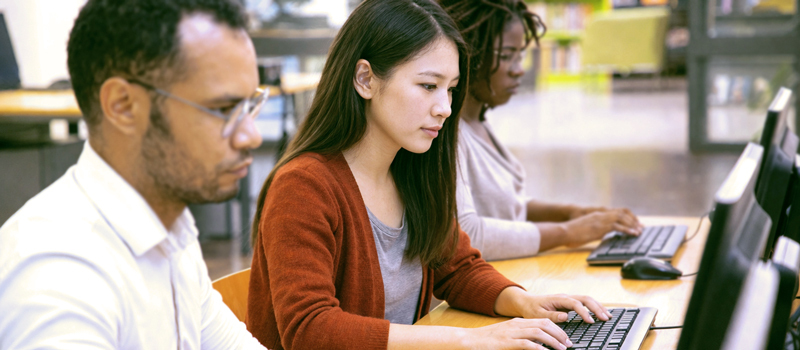 Adult newcomer taking an English assessment test on a computer for LINC placement.